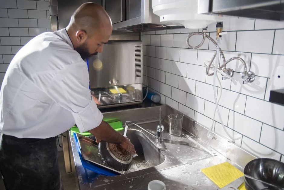 A modern kitchen undergoing renovation, featuring a worker, tools, and materials.